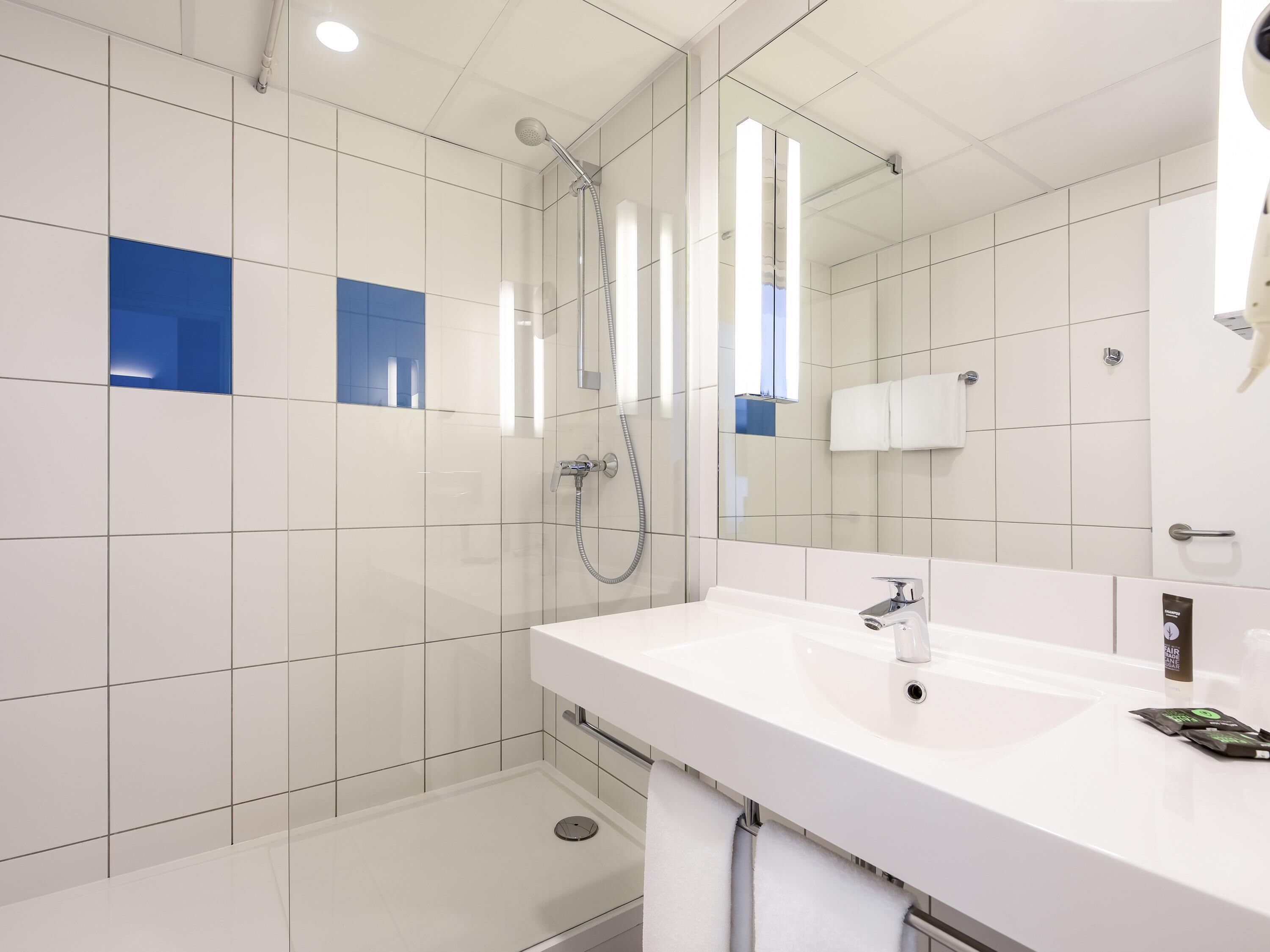 A modern bathroom with a shower, a sink, and a mirror.