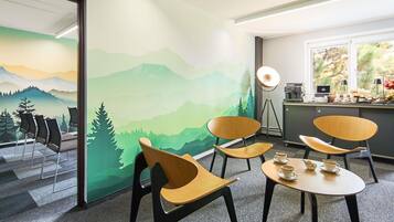 A room with a mural of mountains, a desk with a lamp, and chairs.