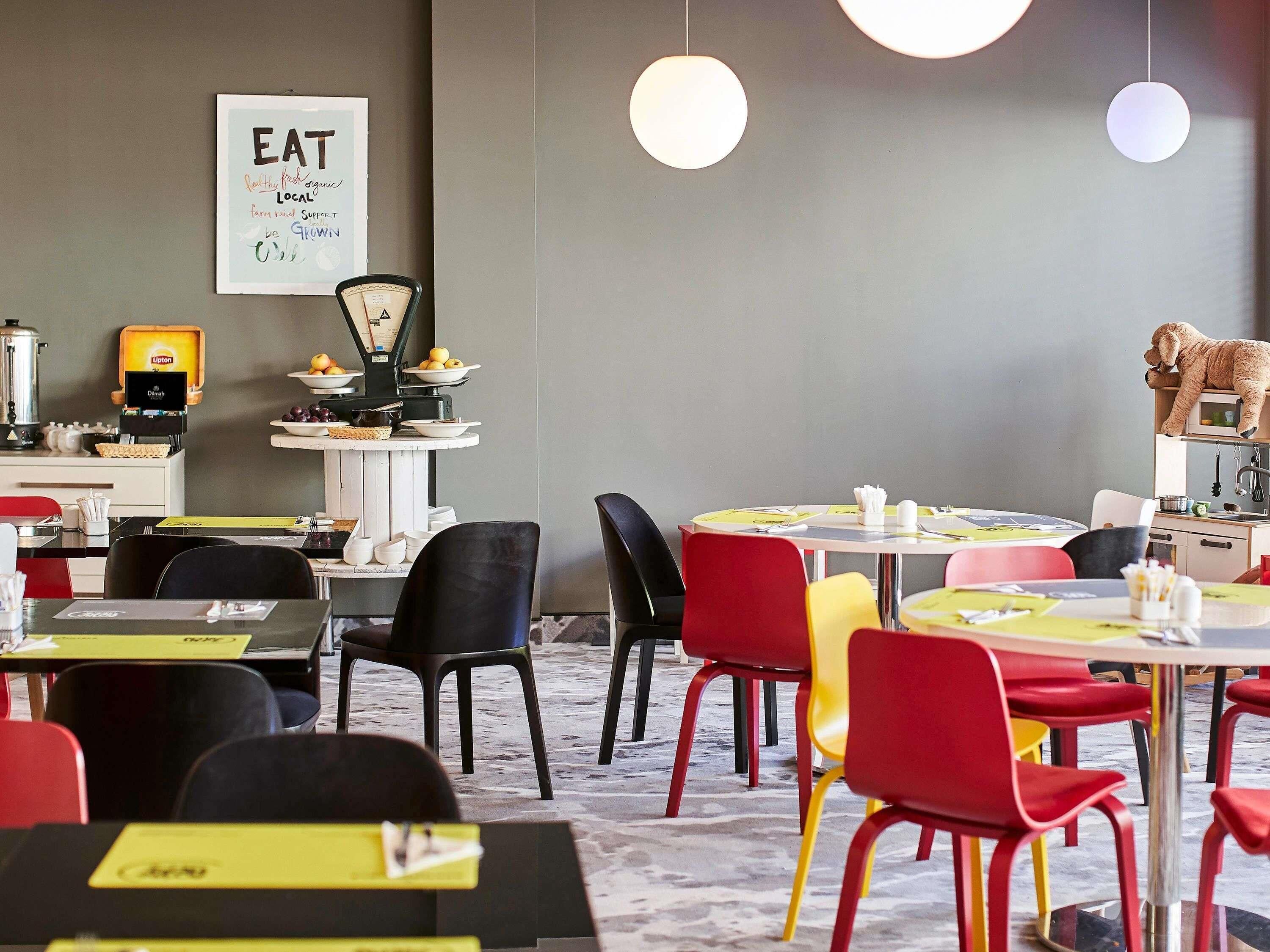 A restaurant interior with tables, chairs, a coffee machine, and a wall sign.