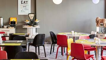A restaurant interior with tables, chairs, a coffee machine, and a wall sign.