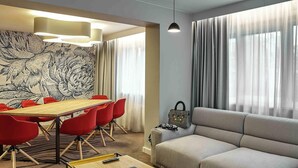A modern living room with a sofa, a coffee table, and a dining area with a table and chairs.