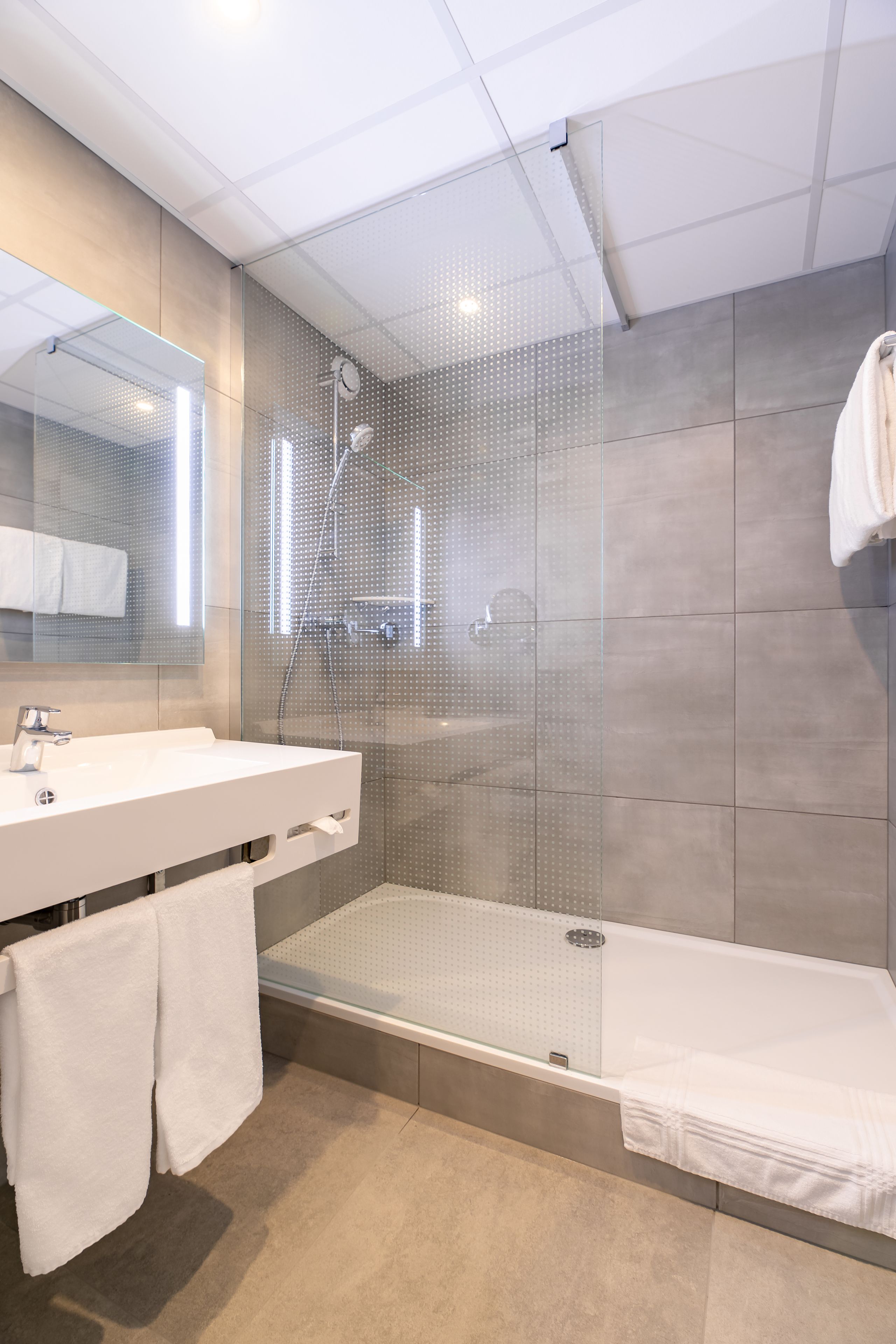 A modern bathroom with a glass-enclosed shower, a white sink, and a bathtub.