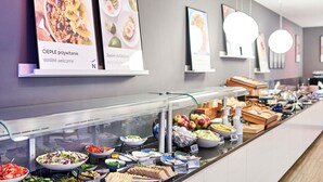 A buffet area with various food options, a wall-mounted menu, and a modern interior design.