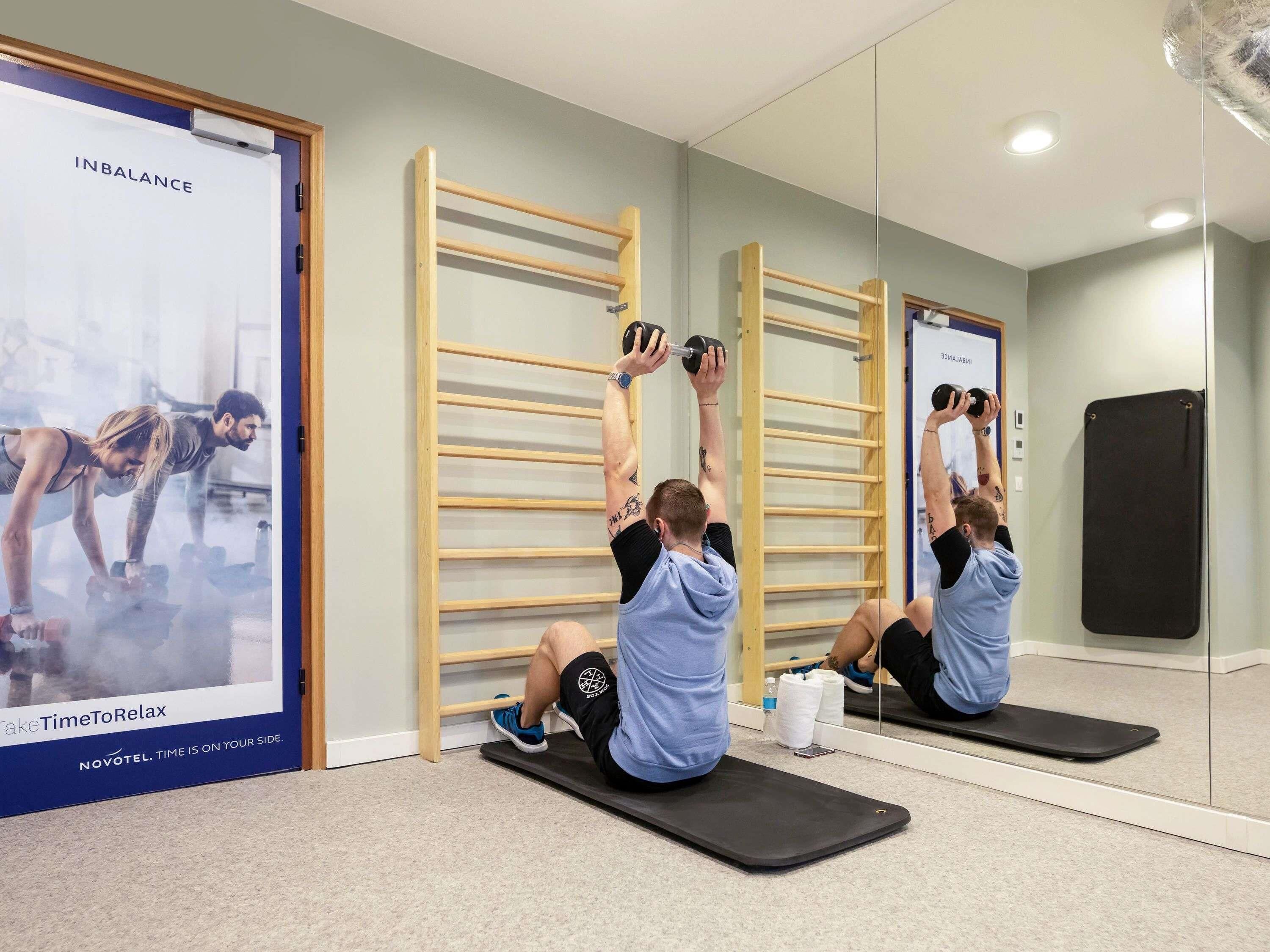 Ein Fitnessraum mit Trainingsgeräten, einem Spiegel und einer Wand mit einem Poster.