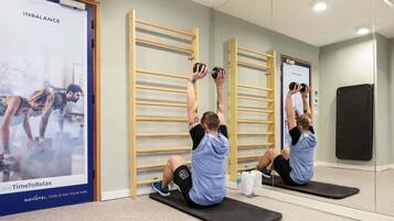Ein Fitnessraum mit Trainingsgeräten, einem Spiegel und einer Wand mit einem Poster.
