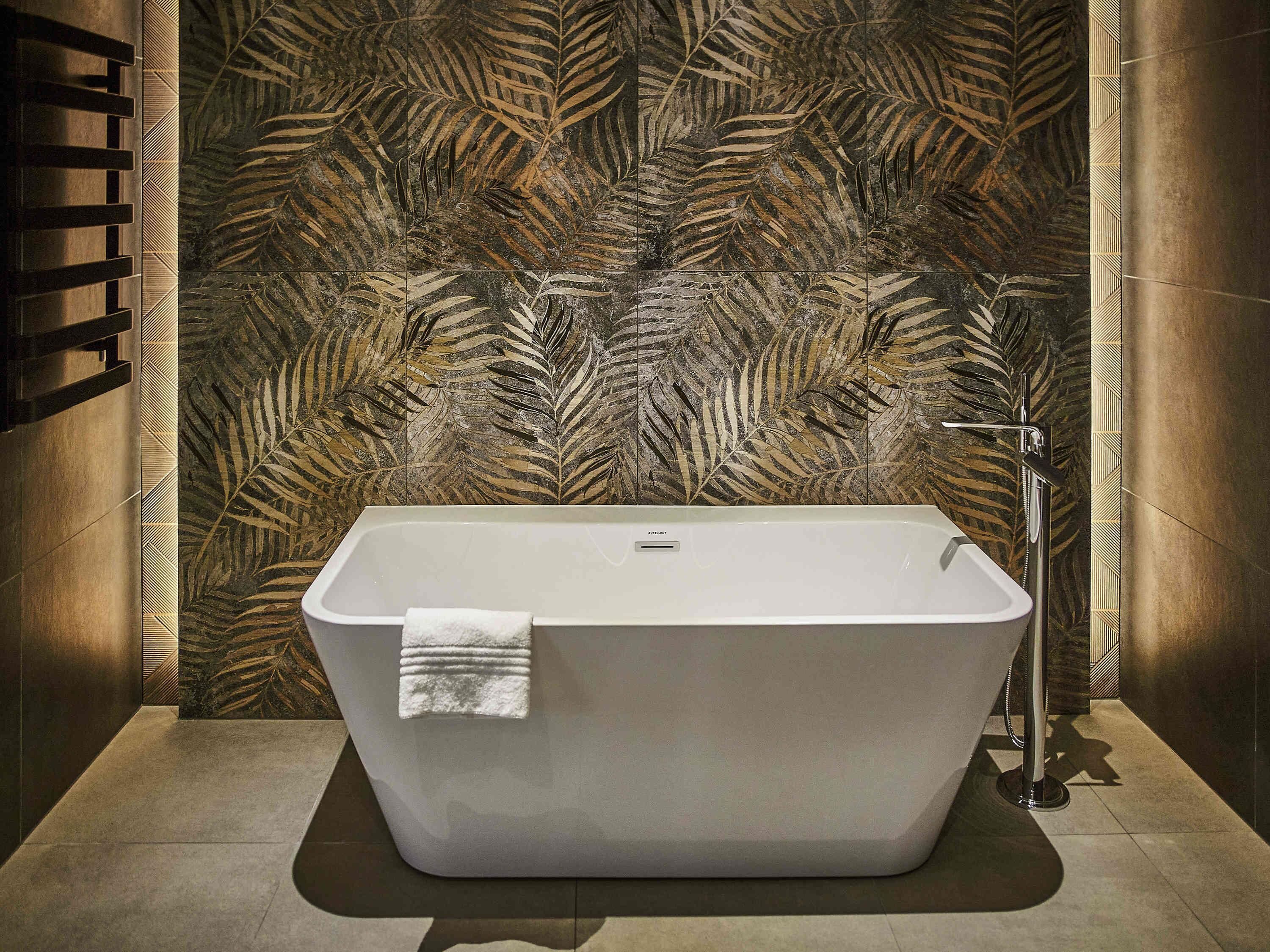 A modern bathroom with a freestanding bathtub, a towel, and a shower area.