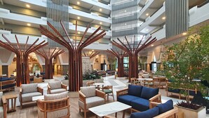 Un vestíbulo amplio con techos altos, mobiliario moderno y una estructura de madera decorativa en el centro.