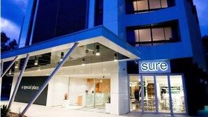 A modern building with a 'sure' sign, featuring a glass storefront and a clear view of the interior. - Mercure Sydney St Leonards (Greenwich)