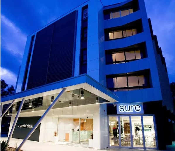 A modern building with a 'sure' sign, featuring a glass storefront and a clear view of the interior. - Mercure Sydney St Leonards (Greenwich)