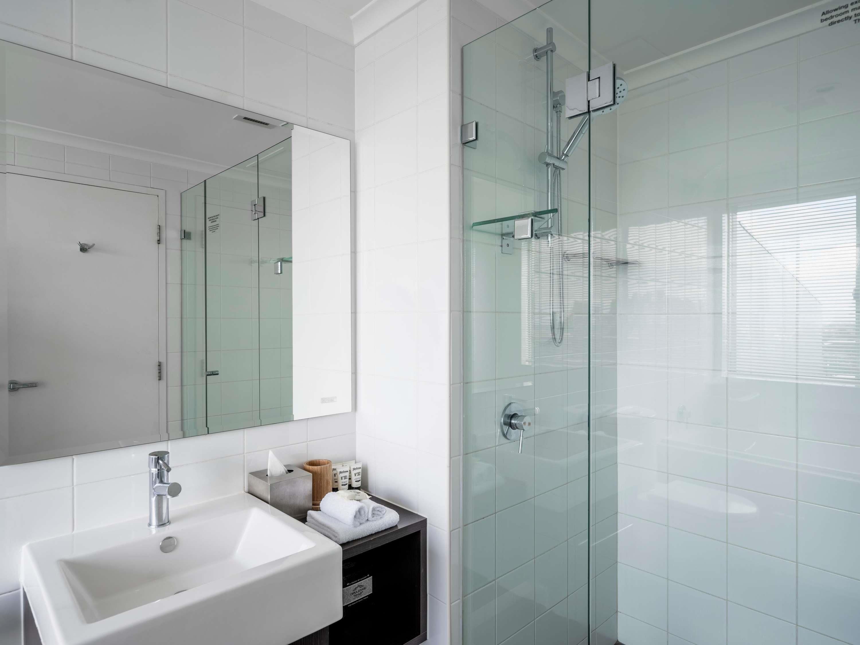 Un baño moderno con cabina de ducha de vidrio, un lavabo blanco y un espejo.