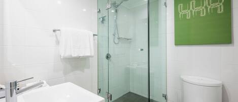 A modern bathroom with a glass-enclosed shower, a white sink, and a toilet.