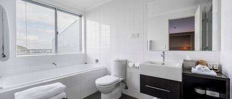A modern bathroom with a bathtub, toilet, and vanity.