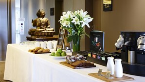 A buffet table with various food items, a Buddha statue, and a coffee machine. - Mercure Sydney St Leonards (Greenwich)