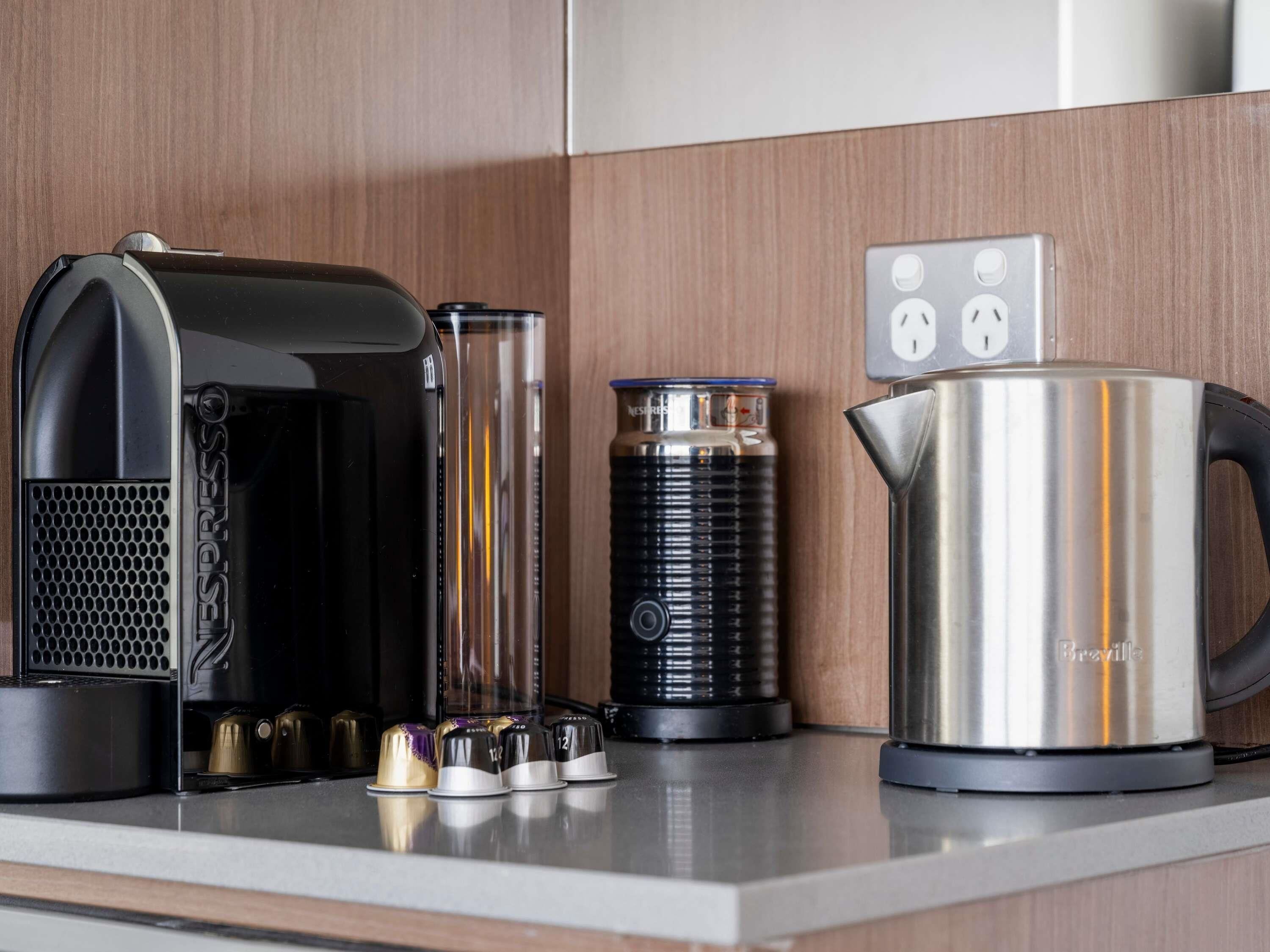 A coffee maker, a thermos, and a kettle on a kitchen counter.