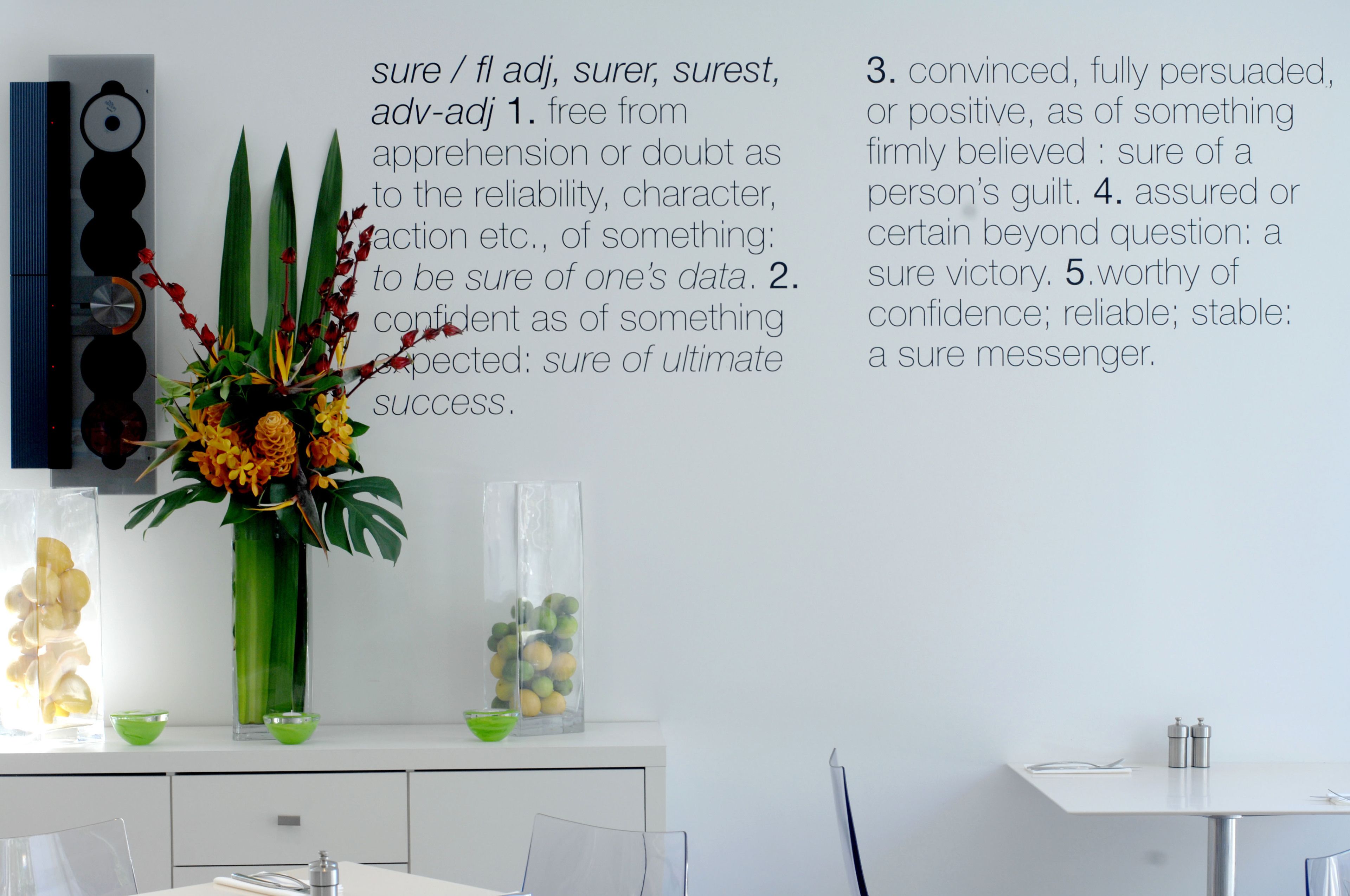 A modern room with a white desk, a vase with flowers, and a wall-mounted clock.
