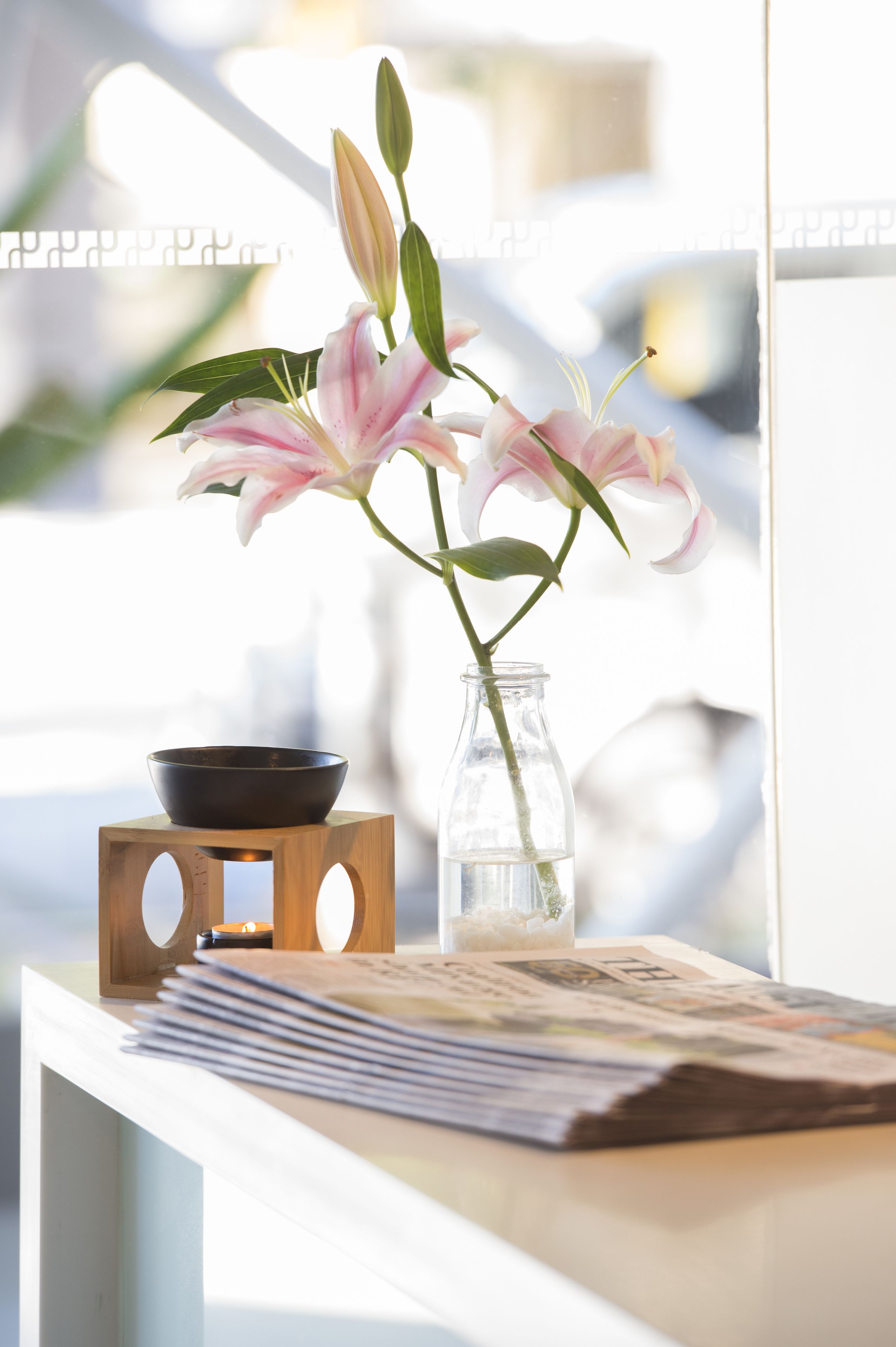 Ein Holztisch mit einer Schale, einer Glasvase mit Blumen und einer Zeitung.
