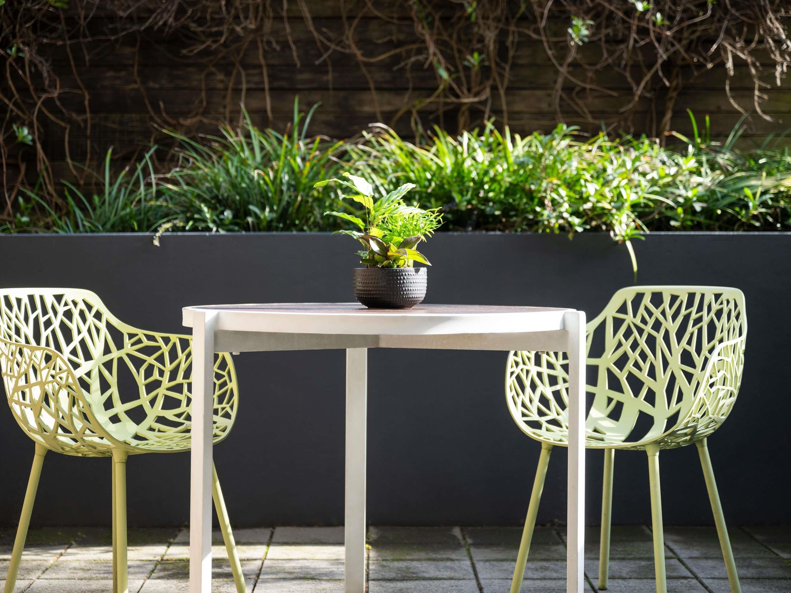 A table with two chairs in a garden setting.