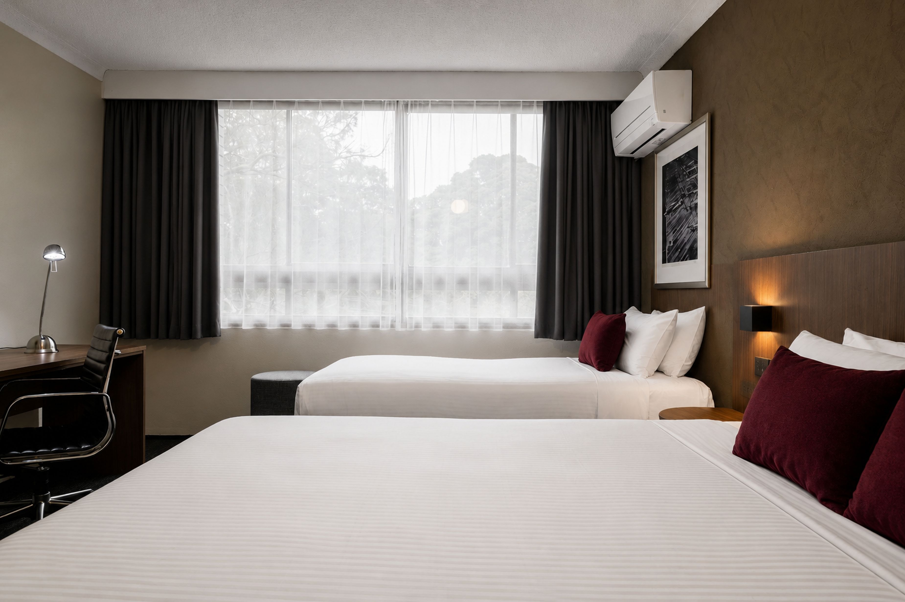 A hotel room with two beds, a desk, and a chair.