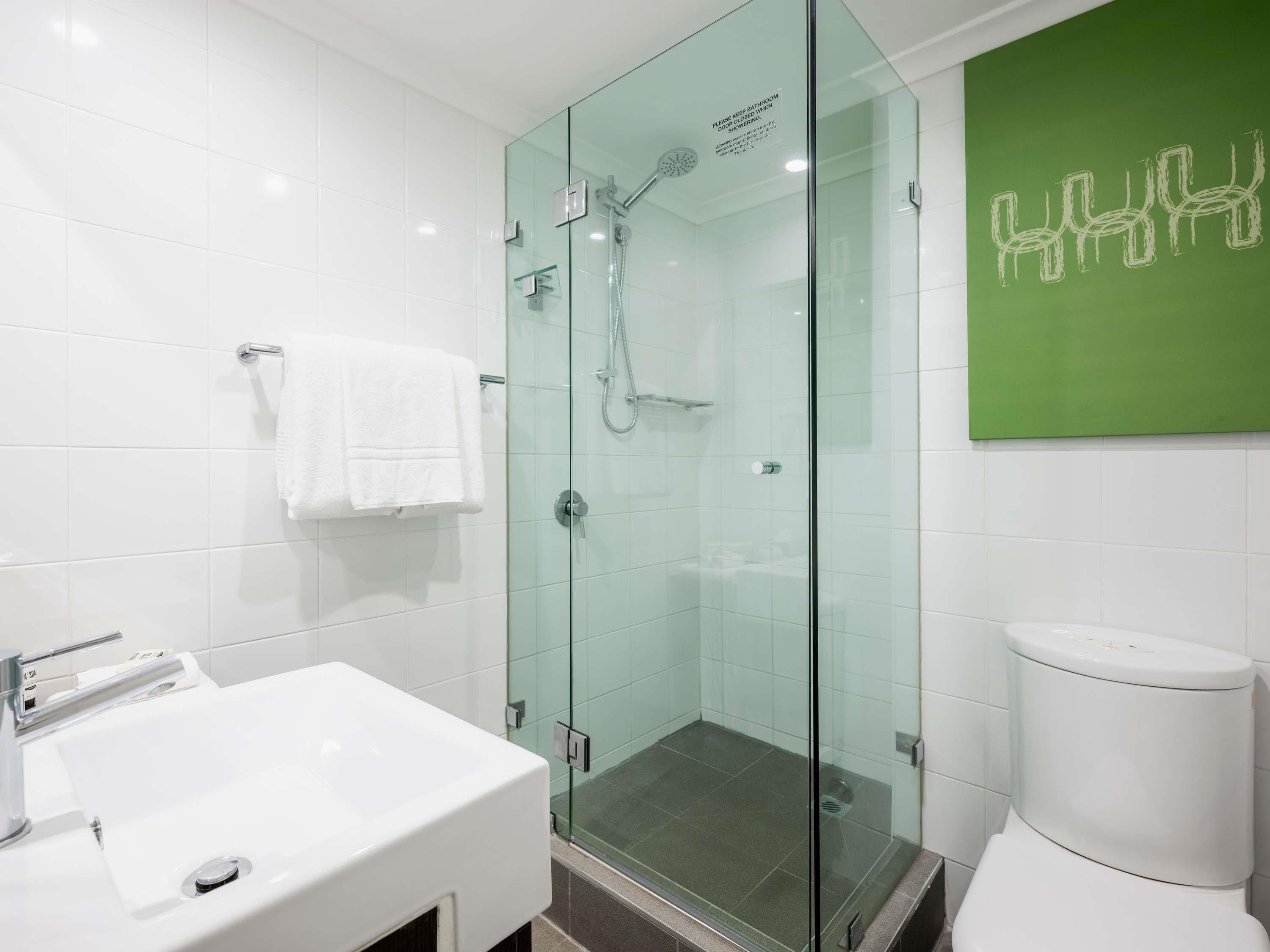 A modern bathroom with a glass-enclosed shower, a white sink, and a toilet.