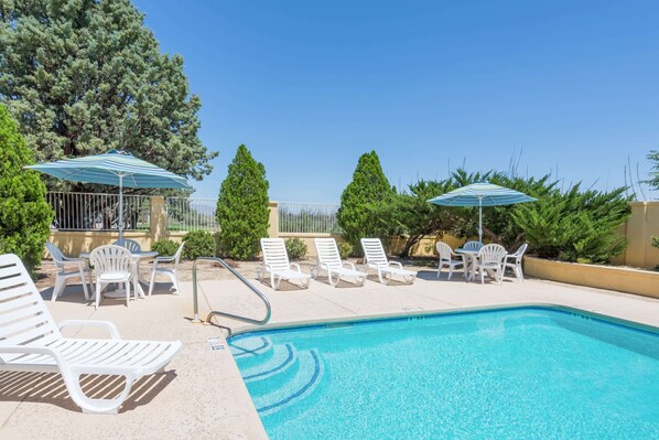 Una piscina al aire libre, sillones reclinables de piscina