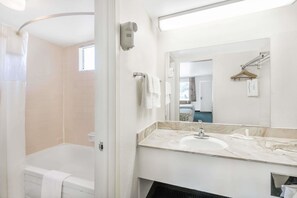 A modern bathroom with a bathtub, a sink, and a mirror. - Days Inn by Wyndham Deming (Deming)