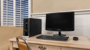 A wooden desk with a desktop computer, a keyboard, and a mouse.