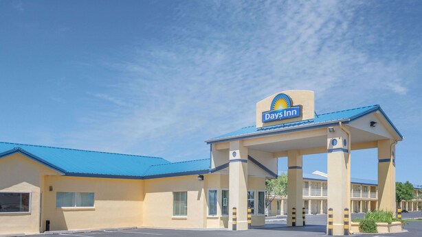 A Days Inn with a blue roof and a yellow facade, featuring a prominent sign above the entrance.