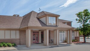Une maison à deux étages avec un garage, une véranda et une porte rouge.