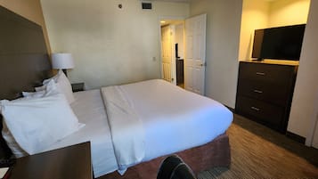 Une chambre d’hôtel comprenant un lit, un bureau avec une lampe, une commode et un téléviseur.