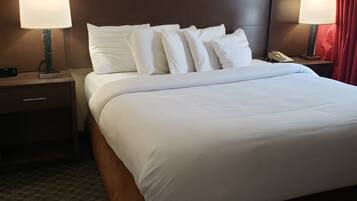 A hotel room with a large bed, two bedside tables with lamps, a telephone, and a red curtain.