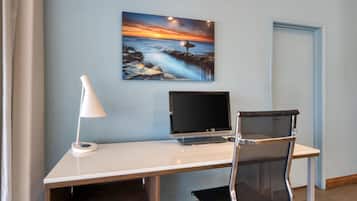 A modern office desk with a computer, a lamp, and a chair in a room with light blue walls.