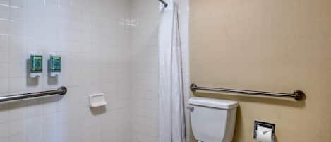Un baño con ducha, inodoro y dispensadores de jabón para manos.