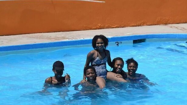 Een zwembad met vier personen in het water.