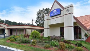 Een hotel met een bord waarop 'Americas Best Value Inn' staat. Het heeft een modern ontwerp, een opvallende ingang en een aangelegde tuin ervoor.