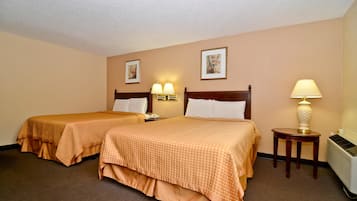 A hotel room with two beds, each with a matching headboard and footboard, a bedside table with a lamp, and a wall-mounted heater.