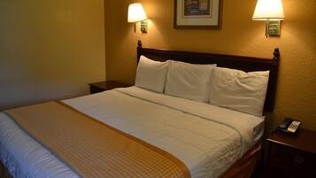 Una cama bien hecha con cabecera de madera, dos lámparas de noche y un teléfono en la mesita.