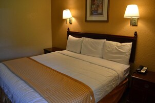 Una cama bien hecha con cabecera de madera, dos lámparas de noche y un teléfono en la mesita.