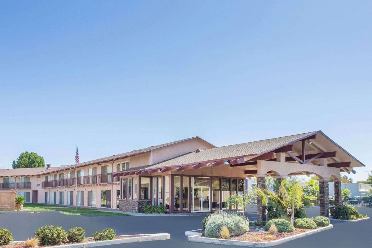 A hotel with a covered entrance, a flag, and a parking lot.