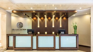 Un mostrador de recepción con un logotipo, tres monitores de computadora y una planta.