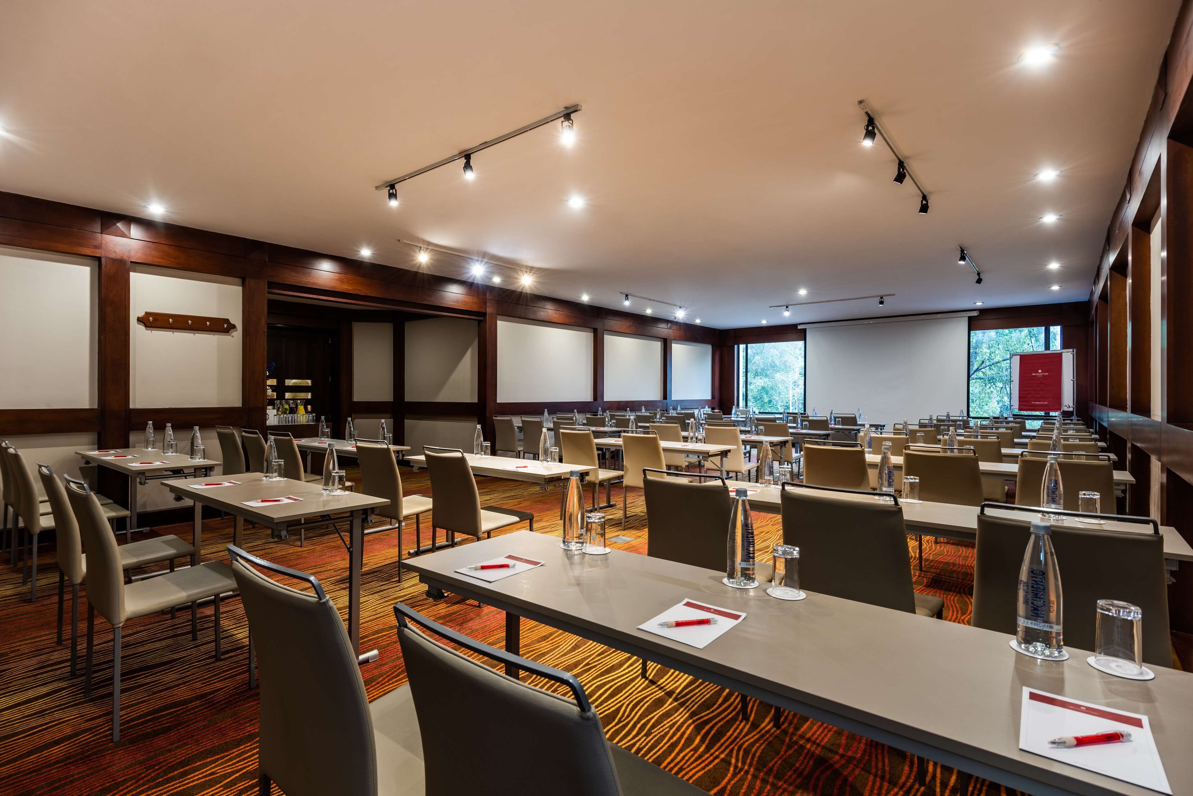 Une salle de conférence dotée de plusieurs tables et chaises, ainsi que de bouteilles d’eau et de porte-noms.