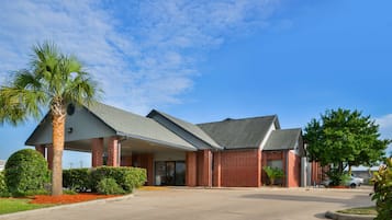Standalone hotel with a red brick facade, covered entrance, and beautifully landscaped surroundings.