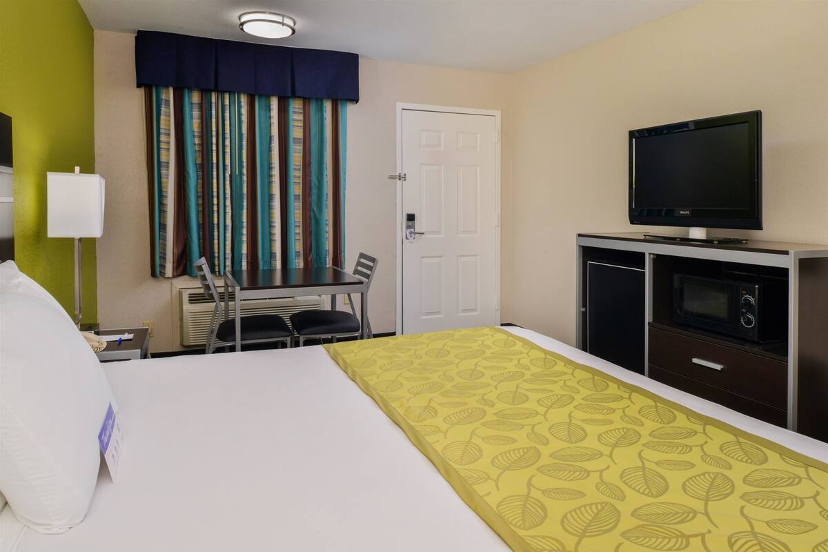 Ein Hotelzimmer mit Bett, Schreibtisch mit Stühlen, Fernseher und Mikrowelle.