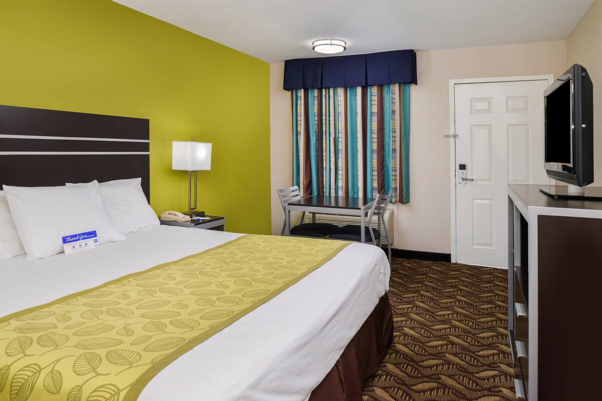 Ein Hotelzimmer mit Bett, Schreibtisch, Fernseher und einer Tür.