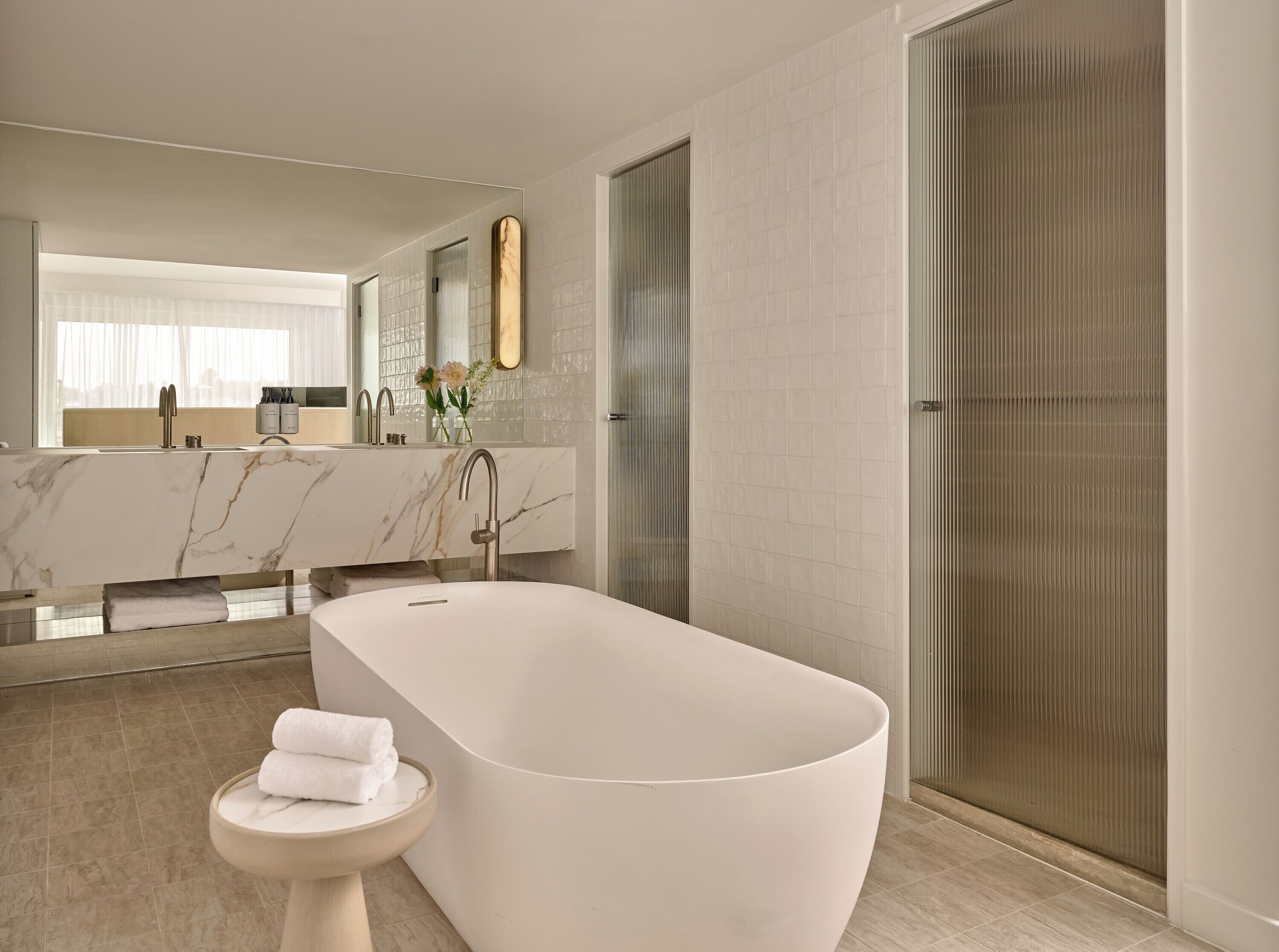 A modern bathroom with a freestanding bathtub, a toilet, and a large mirror above the sink.