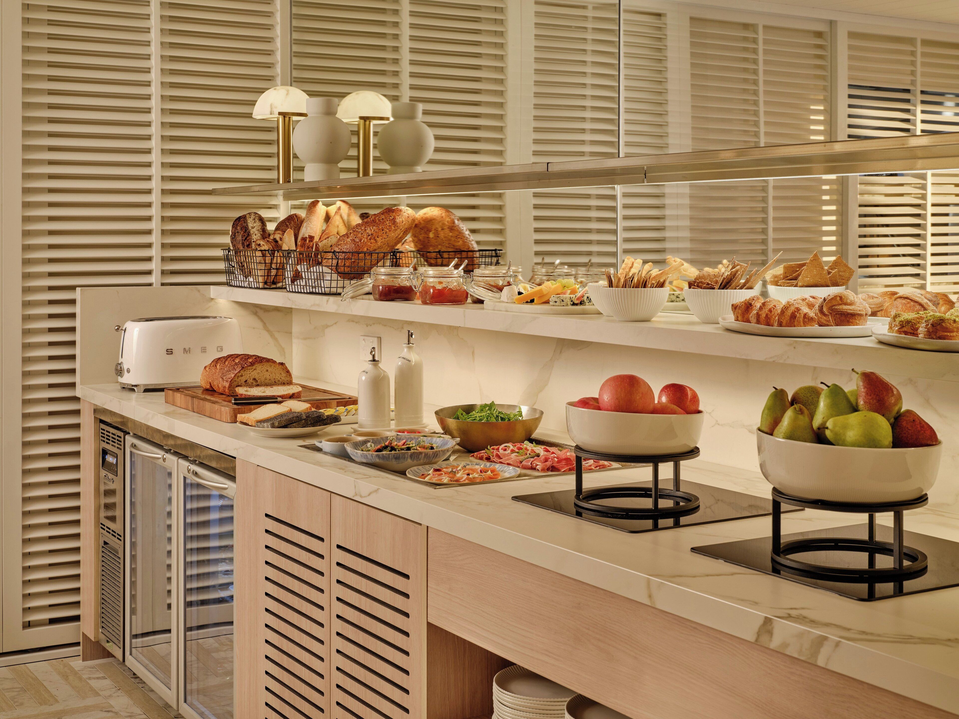 A buffet setup with various food items, a toaster, and a fruit bowl.