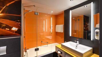 Ein modernes Badezimmer mit einer Glaskabine, einem großen Spiegel und einer gelben Kommode mit Waschbecken in Weiß.