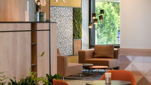 A modern interior with a sofa, chairs, a small table, and a decorative wall with a letter 'M'. - Mercure Hotel Köln West (Cologne)