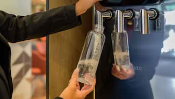 Una persona usando un dispensador de agua con dos grifos, cada uno con una botella.