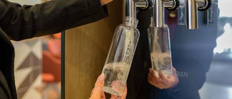 A person operating a water dispenser with two taps, each with a bottle.