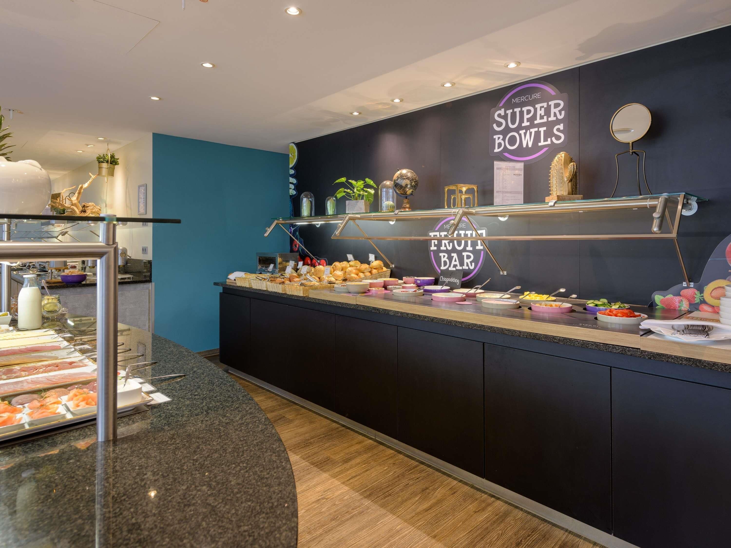 A buffet area with a variety of food items, a fruit bar, and a sign for 'Mercure Super Bowls'.